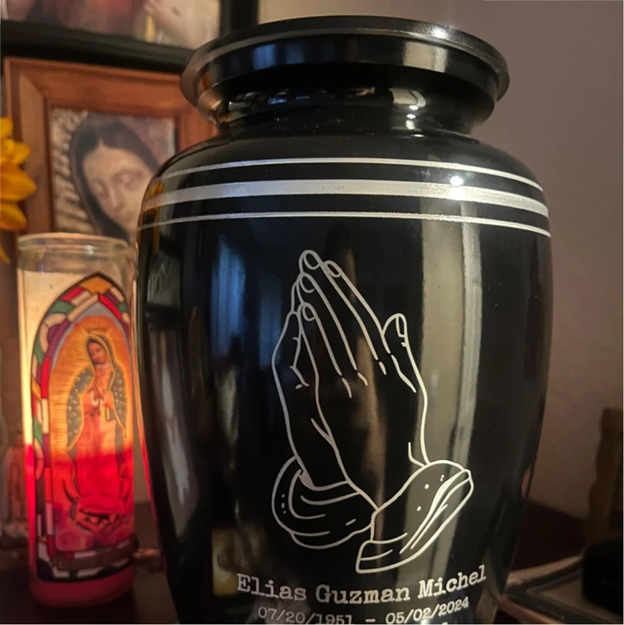 Engraved urn photographed beside candles and framed pictures